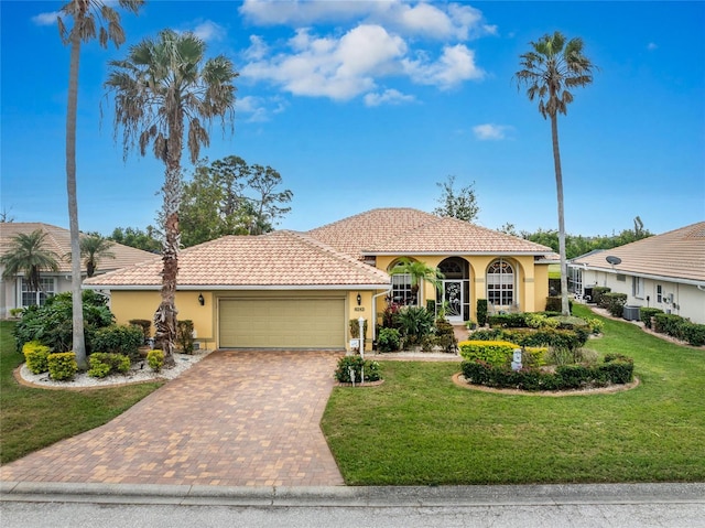 mediterranean / spanish home with a garage and a front lawn