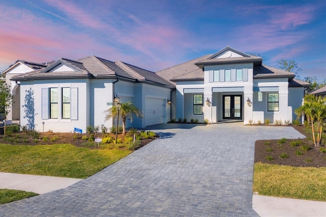 view of front of property featuring a yard, french doors, and a garage