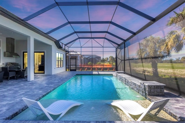 pool at dusk with pool water feature, a grill, a lanai, and a patio