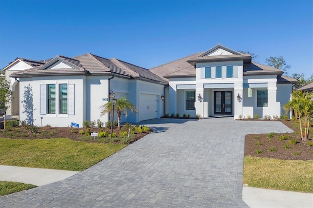 view of front of property featuring french doors, a garage, and a front lawn