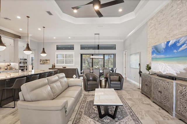 living room with a raised ceiling, ceiling fan, and crown molding