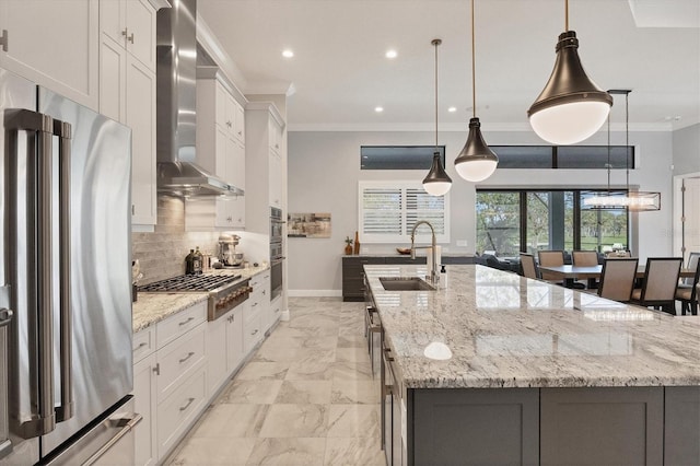 kitchen featuring sink, wall chimney range hood, a spacious island, decorative light fixtures, and appliances with stainless steel finishes