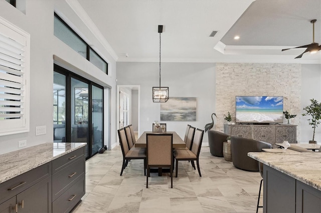 dining area with a tray ceiling, crown molding, and ceiling fan with notable chandelier