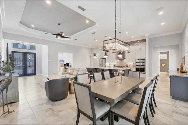 dining room featuring french doors, a tray ceiling, ceiling fan, and crown molding