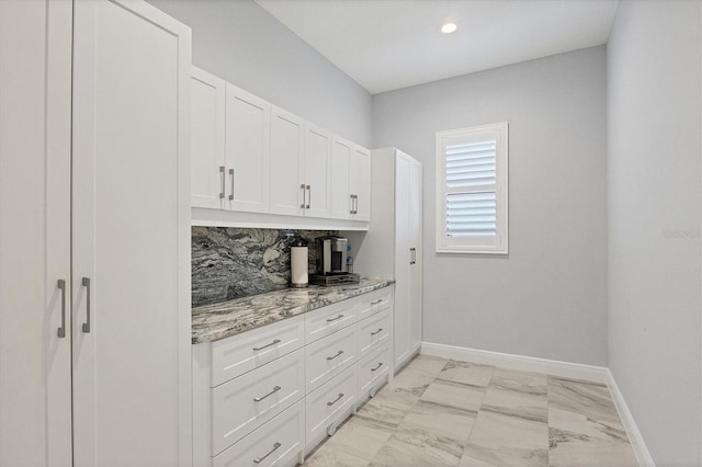 bar featuring decorative backsplash, white cabinetry, and light stone counters