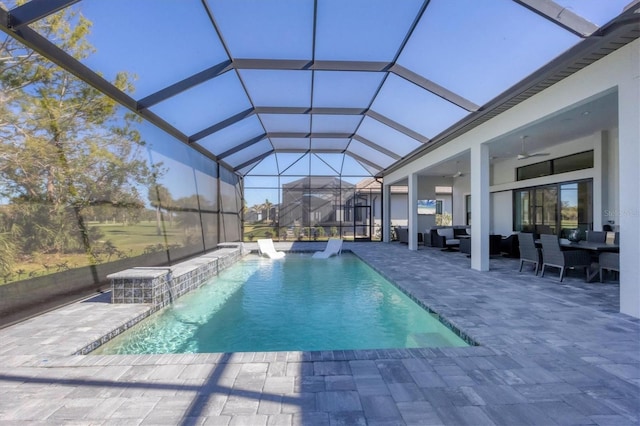 view of pool with glass enclosure, ceiling fan, an outdoor hangout area, pool water feature, and a patio area