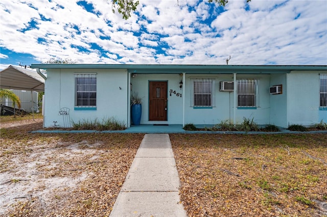 view of front of property with a wall mounted air conditioner and a carport