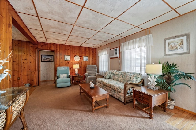 carpeted living room with a wall unit AC and wooden walls