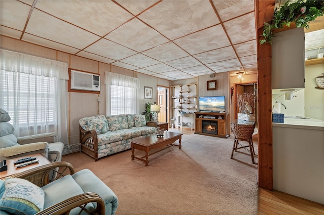 living room featuring a wall mounted AC, wooden walls, and light colored carpet