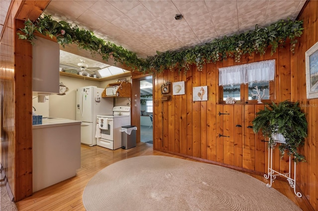 foyer featuring wooden walls, sink, light hardwood / wood-style flooring, and ceiling fan