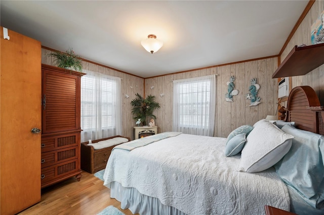 bedroom featuring light wood-type flooring, ornamental molding, and wooden walls