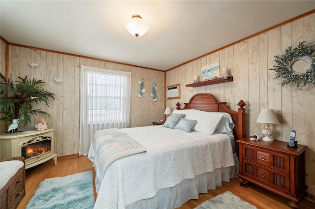 bedroom with an AC wall unit, wood-type flooring, wood walls, and ornamental molding