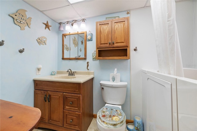 bathroom with a drop ceiling, toilet, and vanity