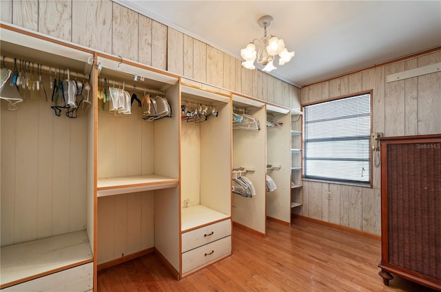 walk in closet featuring light hardwood / wood-style floors and an inviting chandelier