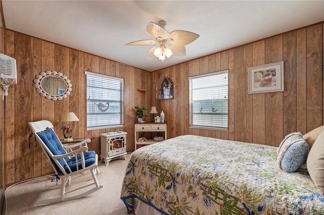 bedroom featuring ceiling fan, multiple windows, carpet, and wooden walls