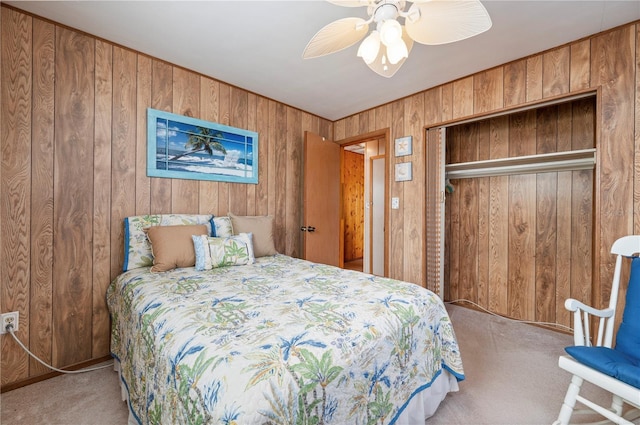 carpeted bedroom featuring wood walls, a closet, and ceiling fan