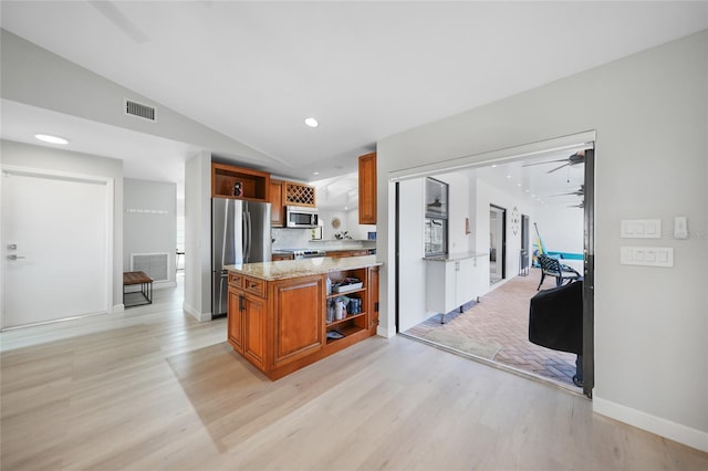 kitchen with stainless steel appliances, vaulted ceiling, light hardwood / wood-style floors, and light stone counters