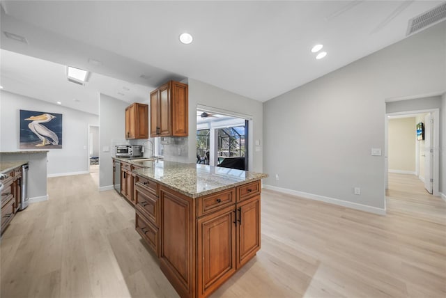 kitchen featuring light wood-type flooring, light stone countertops, and vaulted ceiling