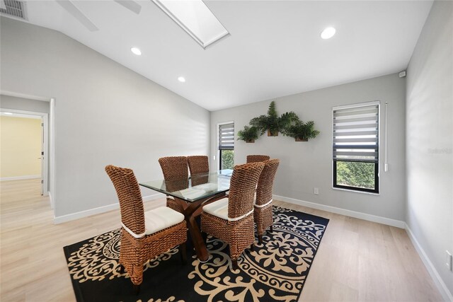 dining area featuring light wood-type flooring, vaulted ceiling, and a healthy amount of sunlight