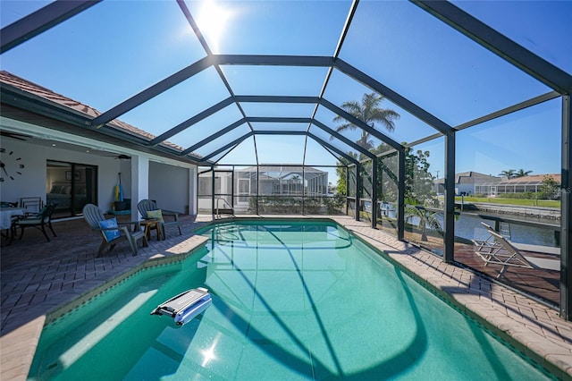 view of pool with a lanai, a patio area, and a water view