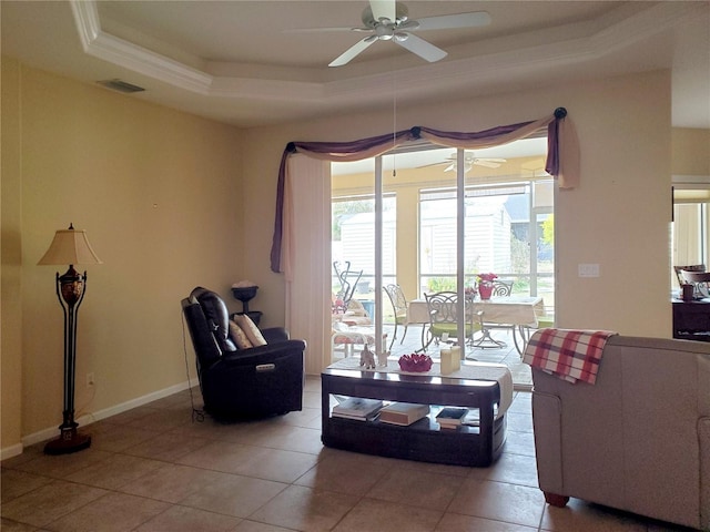 living room with tile patterned flooring, ceiling fan, and a tray ceiling