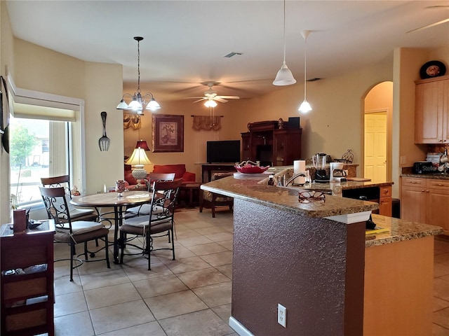 kitchen featuring a kitchen island with sink, hanging light fixtures, light tile patterned floors, light brown cabinets, and ceiling fan with notable chandelier