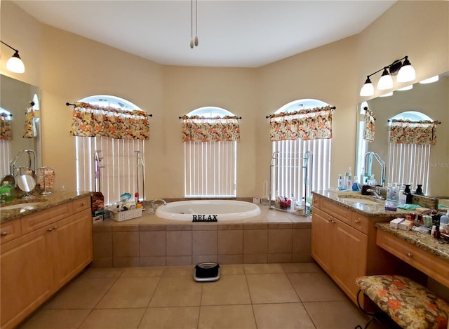 bathroom with tile patterned floors, tiled bath, and vanity