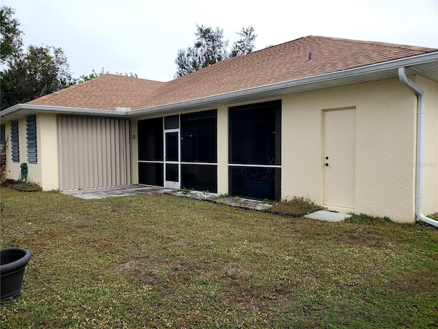 rear view of house with a sunroom and a lawn