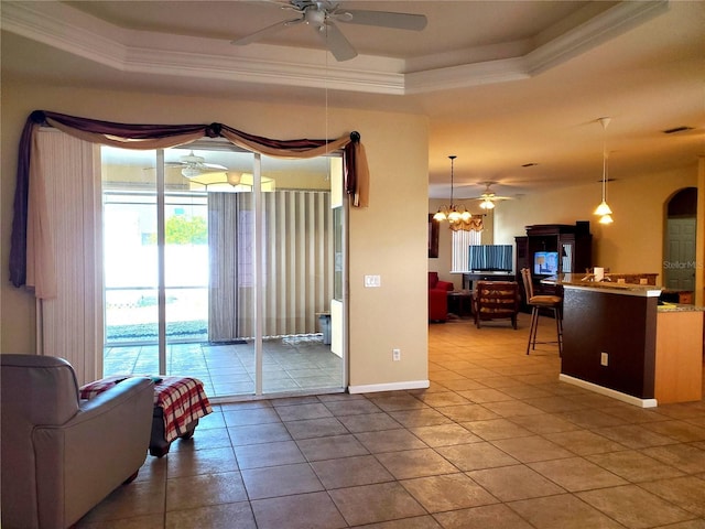 1057 Staley St, Port Charlotte, FL 33952 - living room with tile patterned floors, ceiling fan with notable chandelier, a tray ceiling, and crown molding