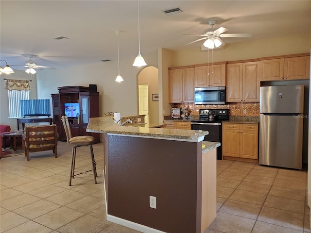 1057 Staley St, Port Charlotte, FL 33952 - kitchen with arched walkways, ceiling fan, stainless steel appliances, and light tile patterned floors