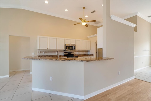 kitchen featuring white cabinetry, appliances with stainless steel finishes, stone countertops, and kitchen peninsula