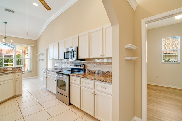 kitchen with pendant lighting, stainless steel appliances, stone countertops, decorative backsplash, and vaulted ceiling