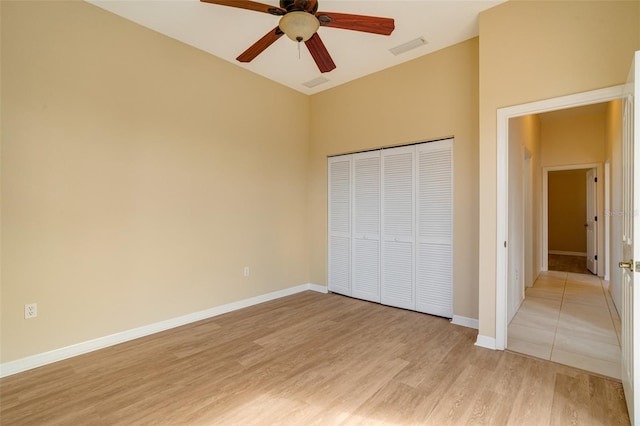 unfurnished bedroom featuring ceiling fan, a closet, and light wood-type flooring