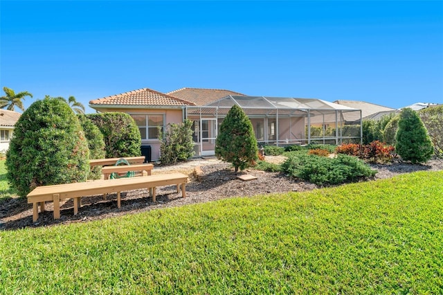 rear view of property with glass enclosure and a lawn