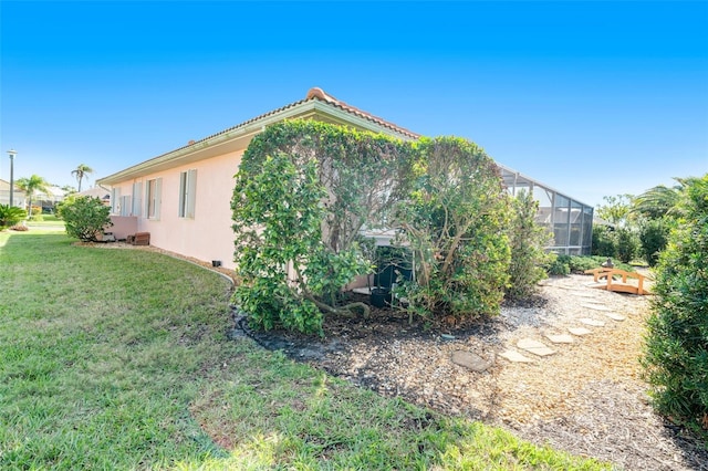 view of side of property with a lanai and a lawn