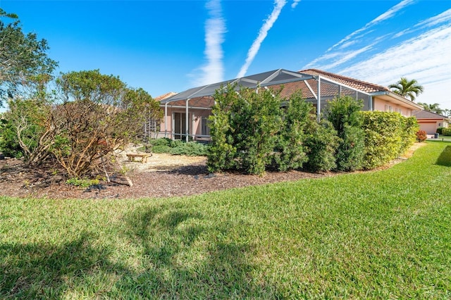 view of side of home with glass enclosure and a lawn