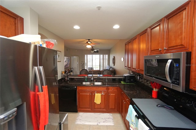 kitchen with dark stone counters, sink, ceiling fan, light tile patterned floors, and stainless steel appliances