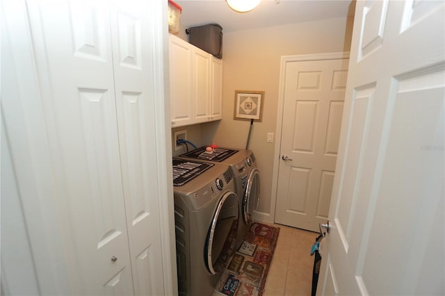 laundry area featuring washer and dryer, light tile patterned flooring, and cabinets