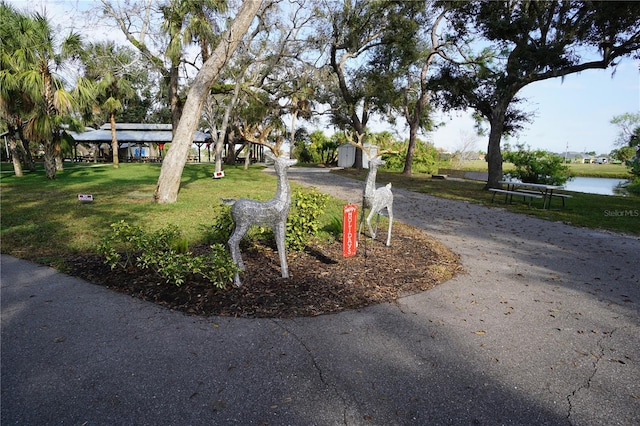 surrounding community with a lawn, a water view, and a storage unit