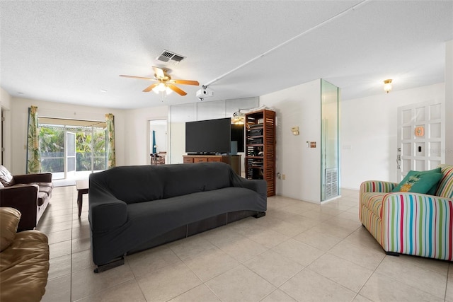 living room with ceiling fan, a textured ceiling, and light tile patterned flooring