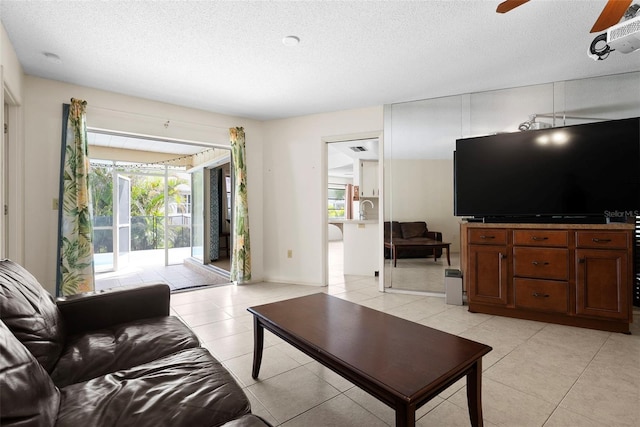 tiled living room featuring ceiling fan, sink, and a textured ceiling