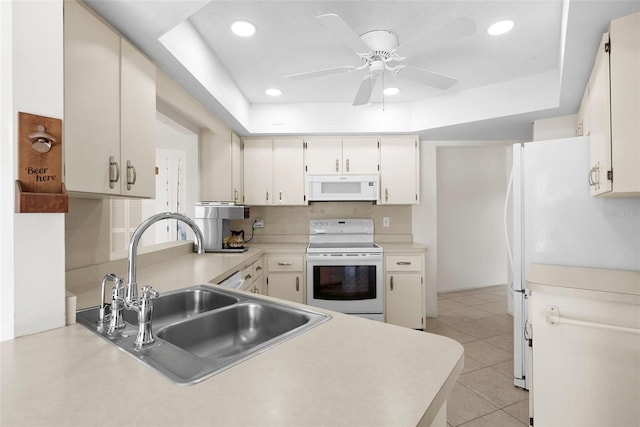 kitchen with sink, white appliances, ceiling fan, light tile patterned flooring, and a raised ceiling