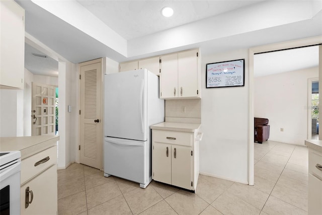 kitchen with white refrigerator, backsplash, and light tile patterned floors