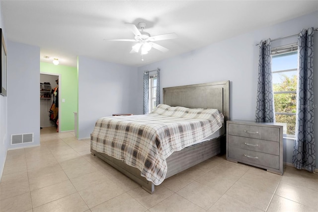 bedroom featuring ceiling fan, a walk in closet, a closet, and light tile patterned floors