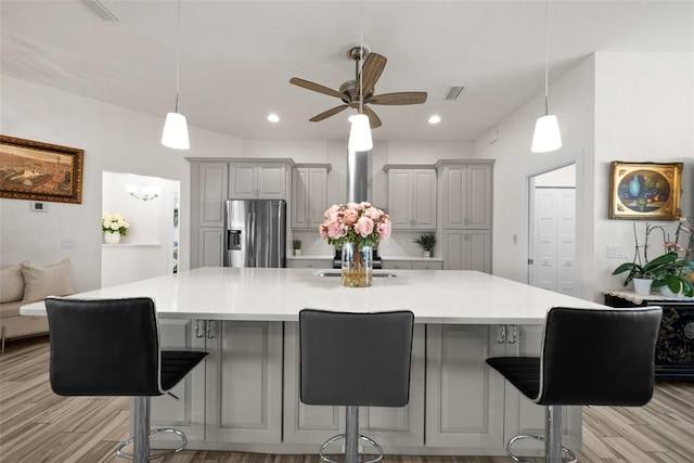 kitchen with gray cabinetry, light hardwood / wood-style flooring, a kitchen breakfast bar, and stainless steel refrigerator with ice dispenser