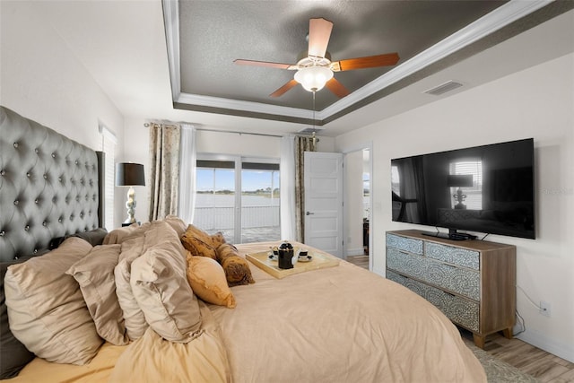 bedroom with wood-type flooring, access to outside, ceiling fan, a raised ceiling, and crown molding