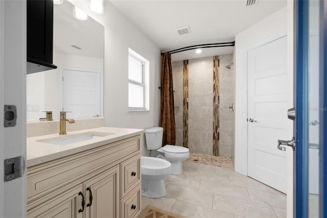 bathroom with a tile shower, tile patterned flooring, vanity, toilet, and a bidet