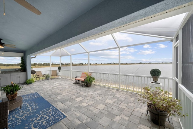 view of patio / terrace featuring a lanai, ceiling fan, and a water view