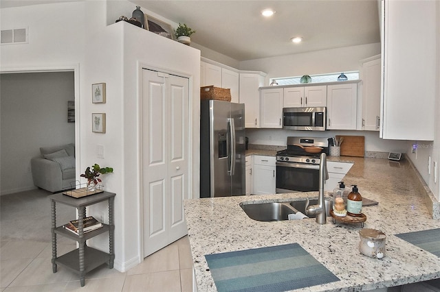 kitchen featuring light stone countertops, white cabinetry, sink, stainless steel appliances, and light tile patterned floors