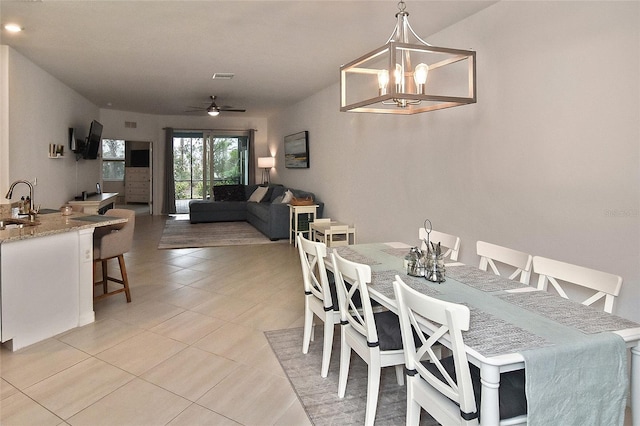 dining area featuring sink, light tile patterned floors, and ceiling fan with notable chandelier